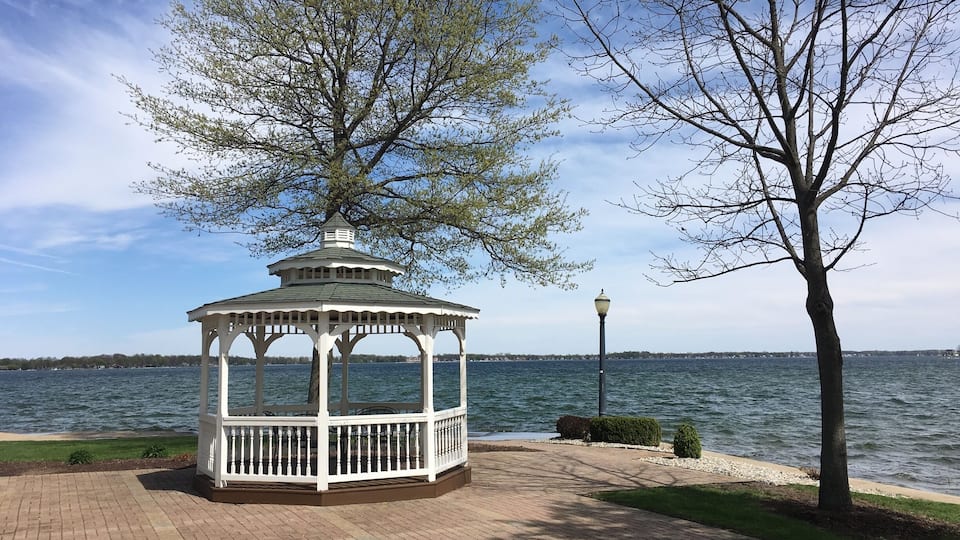 A gazebo by a lake with a clear sky.