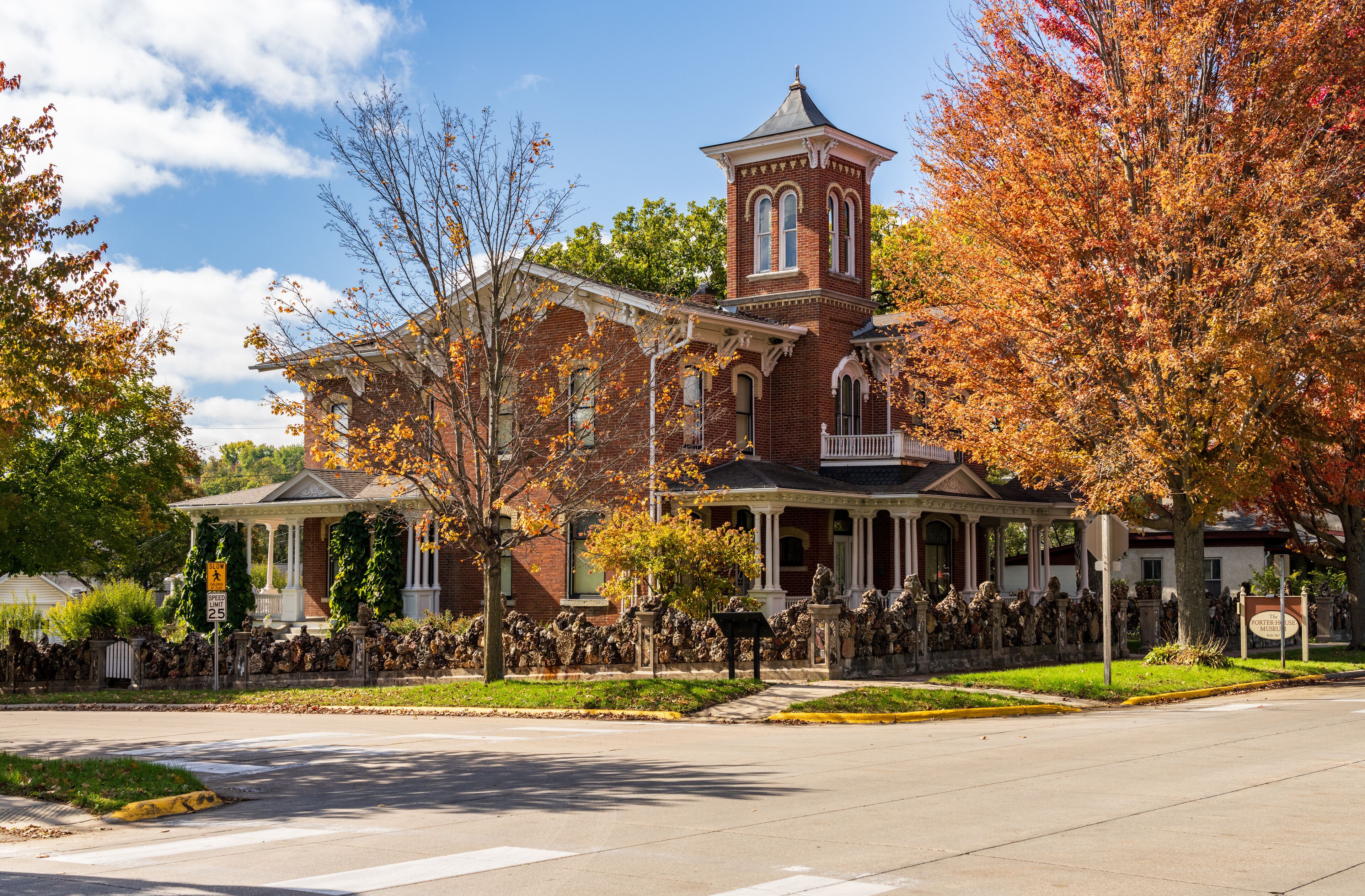 A historic brick building with a tower, surrounded by autumn foliage.
