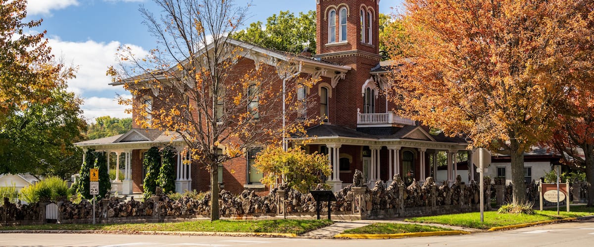 A historic brick building with a tower, surrounded by autumn foliage.