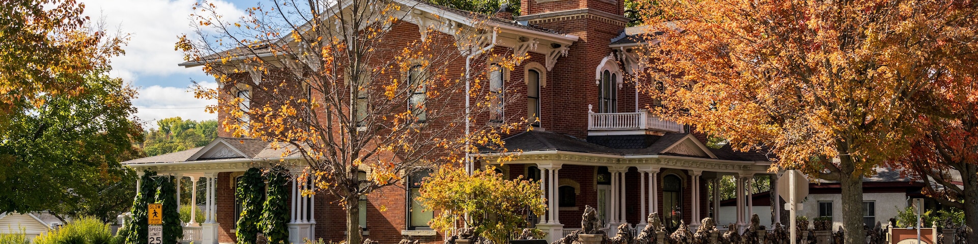 A historic brick building with a tower, surrounded by autumn foliage.
