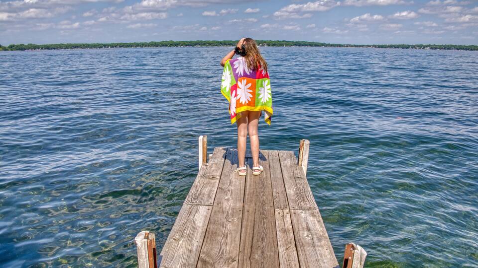 A wooden pier extending into a calm body of water with a clear sky above.