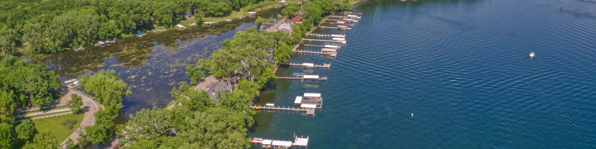 An aerial view of a lakeside community with docks, houses, and lush greenery.