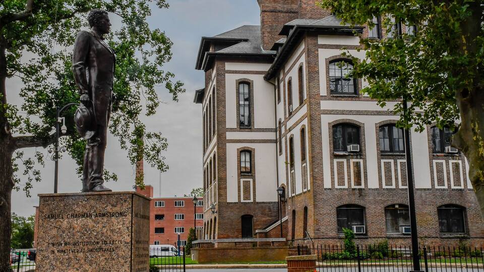 A statue of Samuel Chapman Armstrong, a brick building, and a fence.