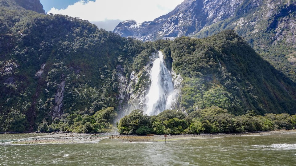 A waterfall cascading down a steep cliff surrounded by dense forest.