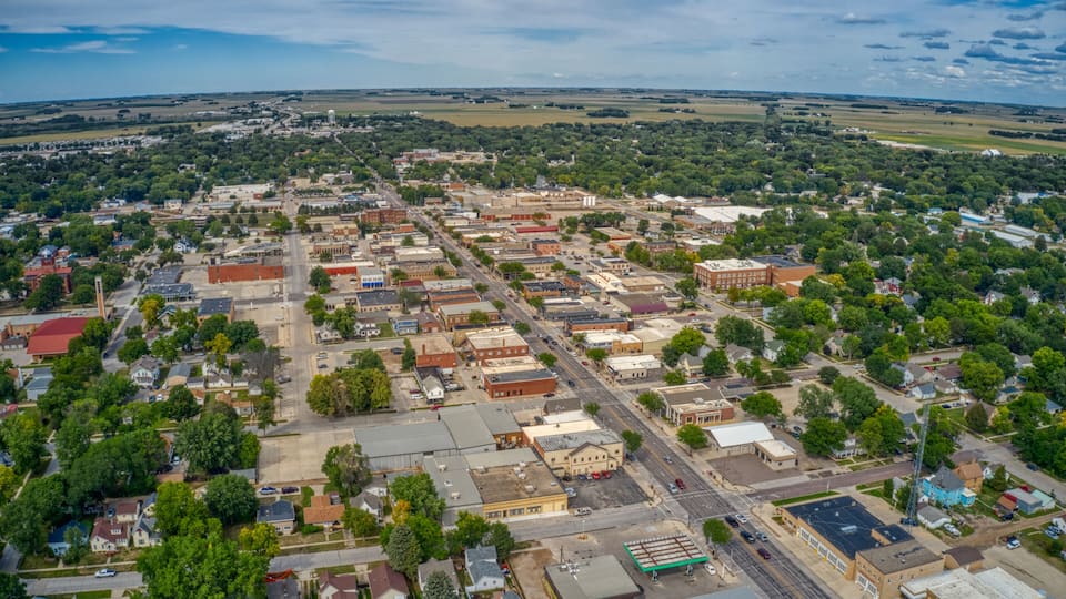 An aerial view of a town with a grid of streets, buildings, and green spaces.