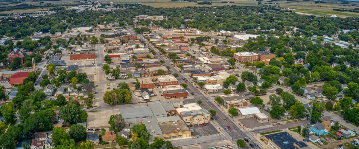An aerial view of a town with a grid of streets, buildings, and green spaces.