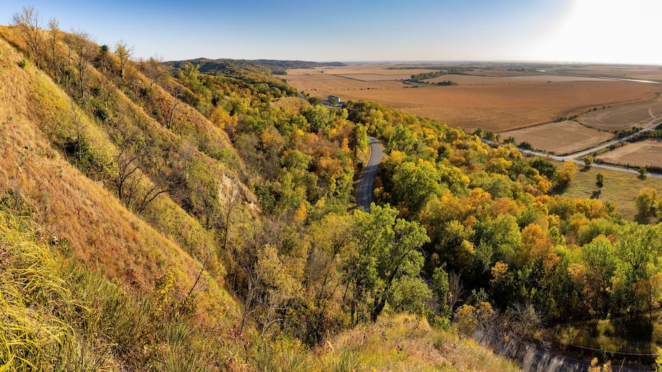 A winding road through a forested valley with autumn foliage.
