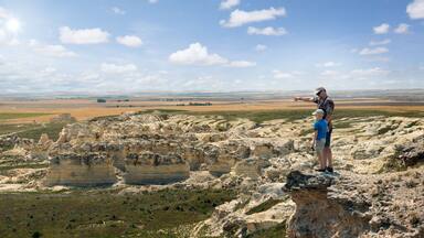 Father and son stand on the rock and look at the horizon line. Castle Rock Badlands. Western Kansas, US