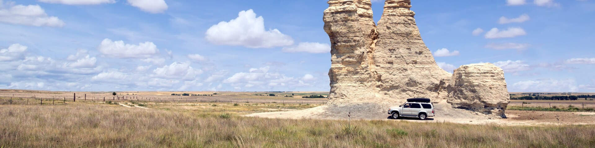 Un paisaje con formaciones rocosas y un vehículo.