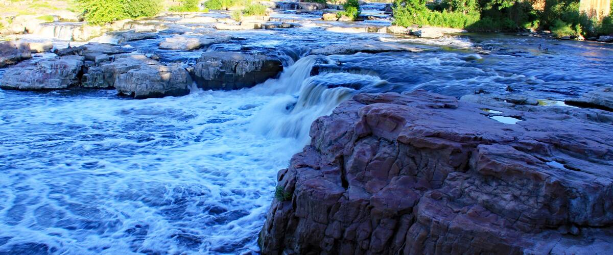 A river with a rocky waterfall and surrounding greenery.