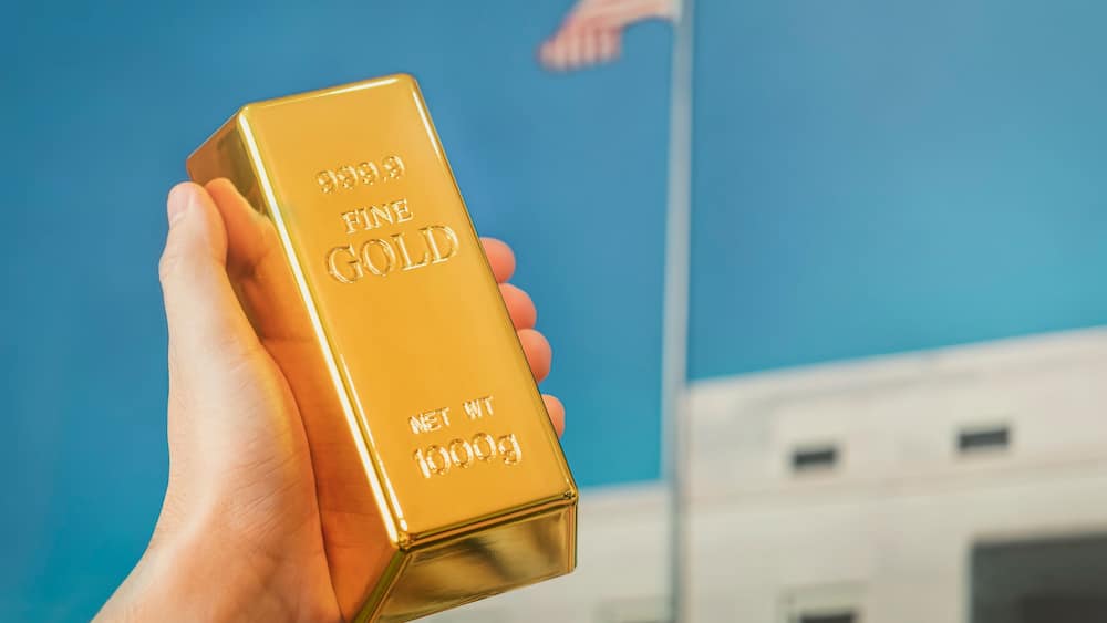 gold bar in the hand of a man against the background of the gold vault of America.