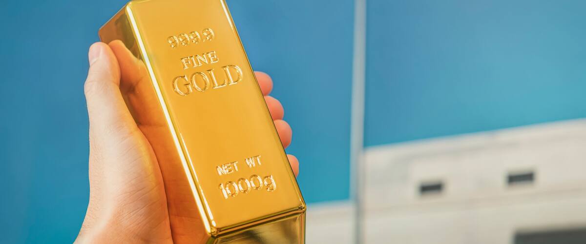 gold bar in the hand of a man against the background of the gold vault of America.