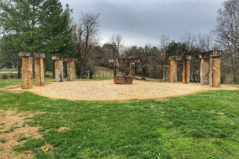 A stone circle with a central structure in a grassy field.