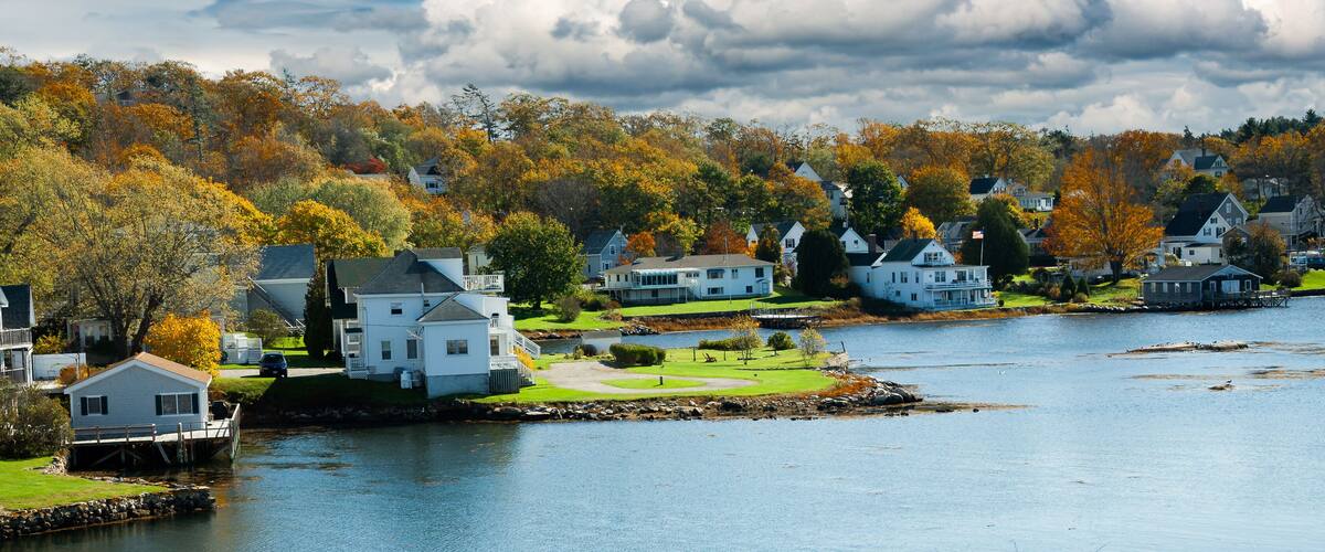 A lakeside community with houses and autumn foliage.