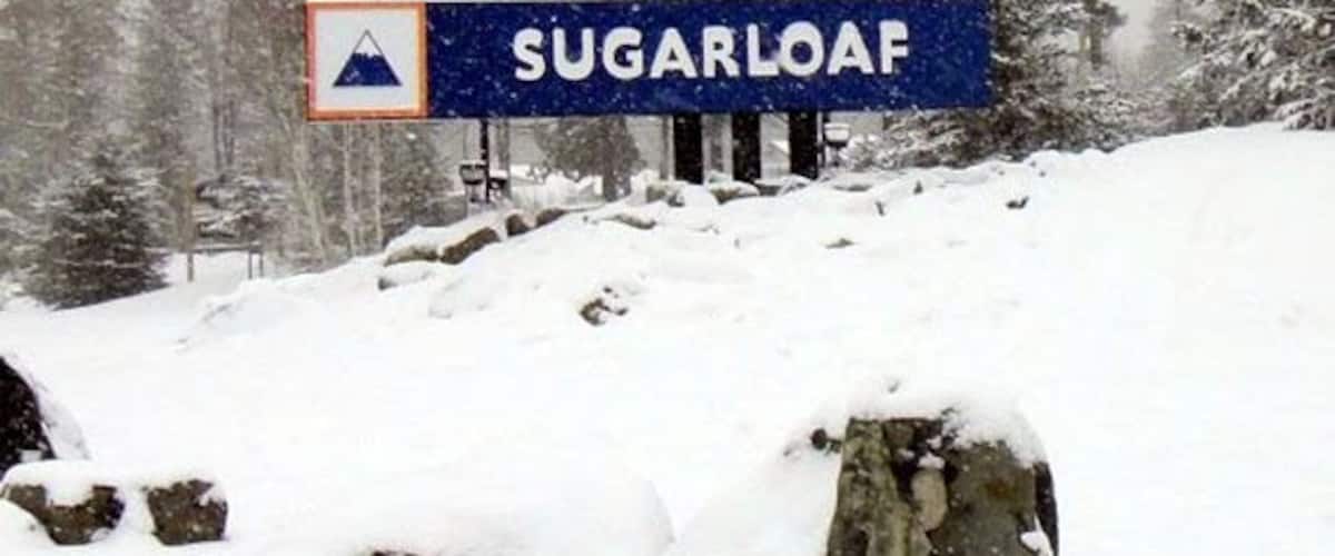 Una montaña nevada con un cartel que dice 'SUGARLOAF'.