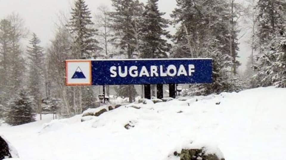 A snow-covered mountain with a sign reading "SUGARLOAF".
