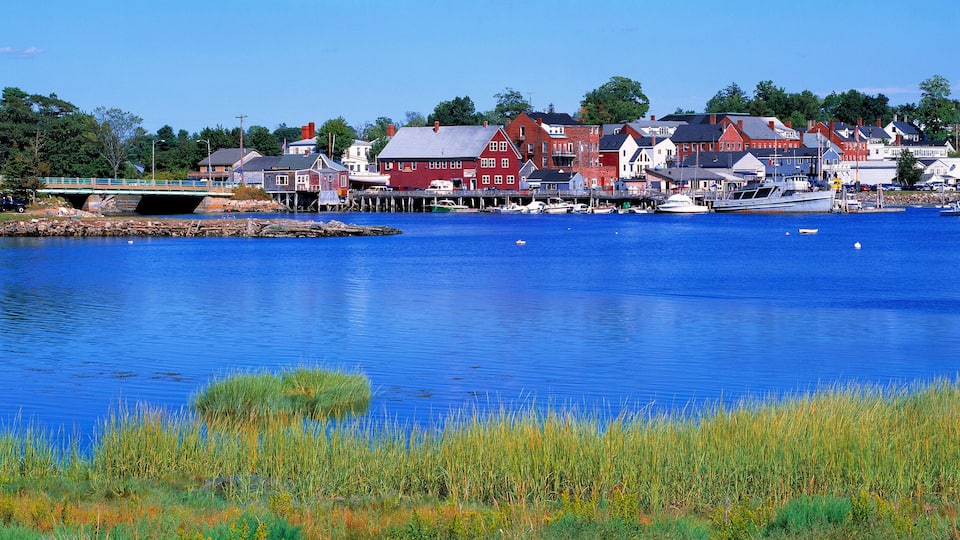 A calm lake with boats, a bridge, and a town with red and white buildings.