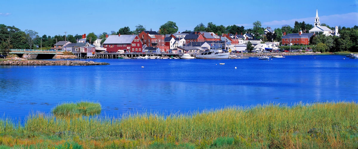 A calm lake with boats, a bridge, and a town with red and white buildings.