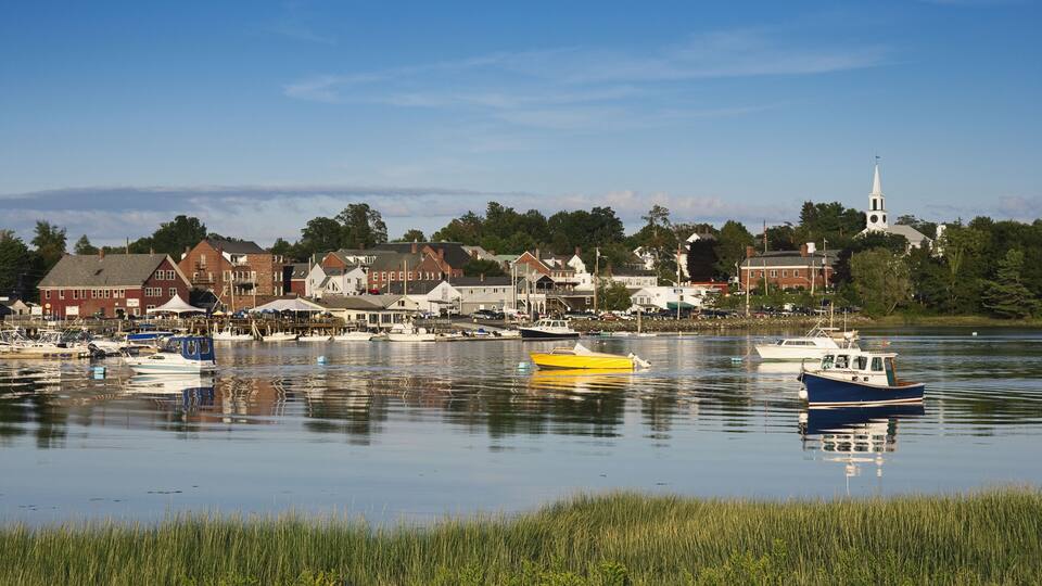 A calm harbor with boats, waterfront buildings, and a church steeple.