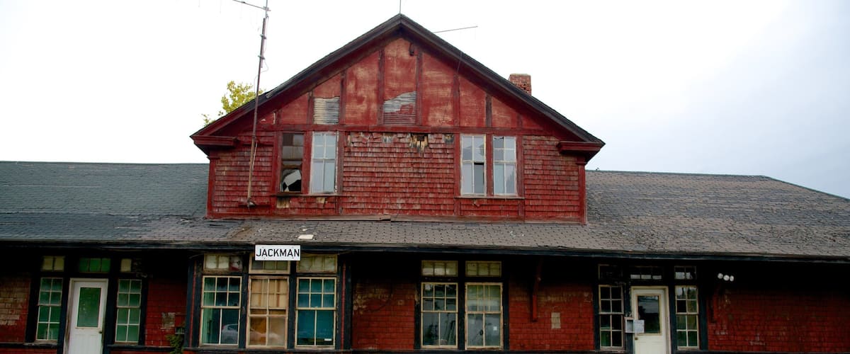 An old red wooden train station with a sign reading "JACKMAN".