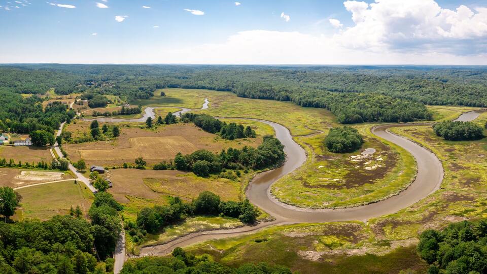 A river winding through a forested valley with scattered buildings and roads.