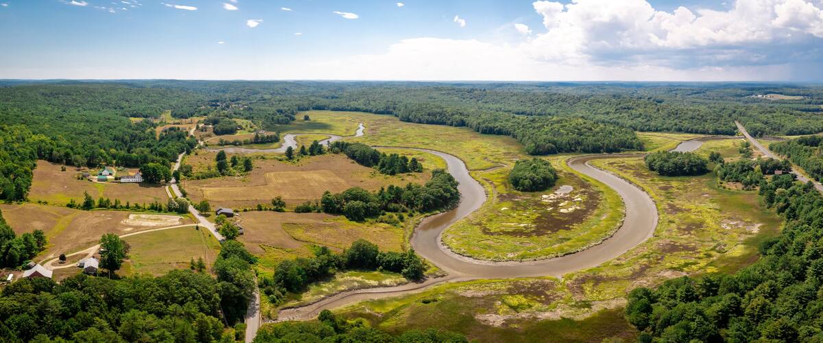 A river winding through a forested valley with scattered buildings and roads.