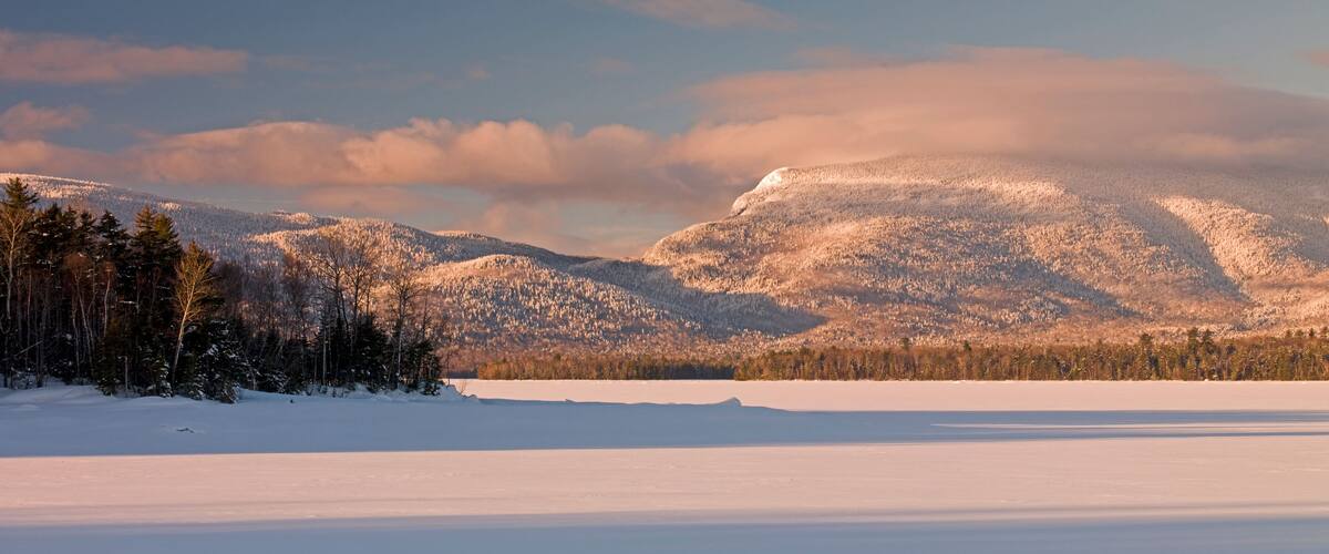 A snow-covered landscape with mountains and a clear sky.