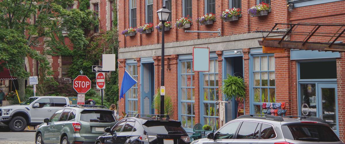 A red brick building with blue trim, a stop sign, and parked cars on the street.