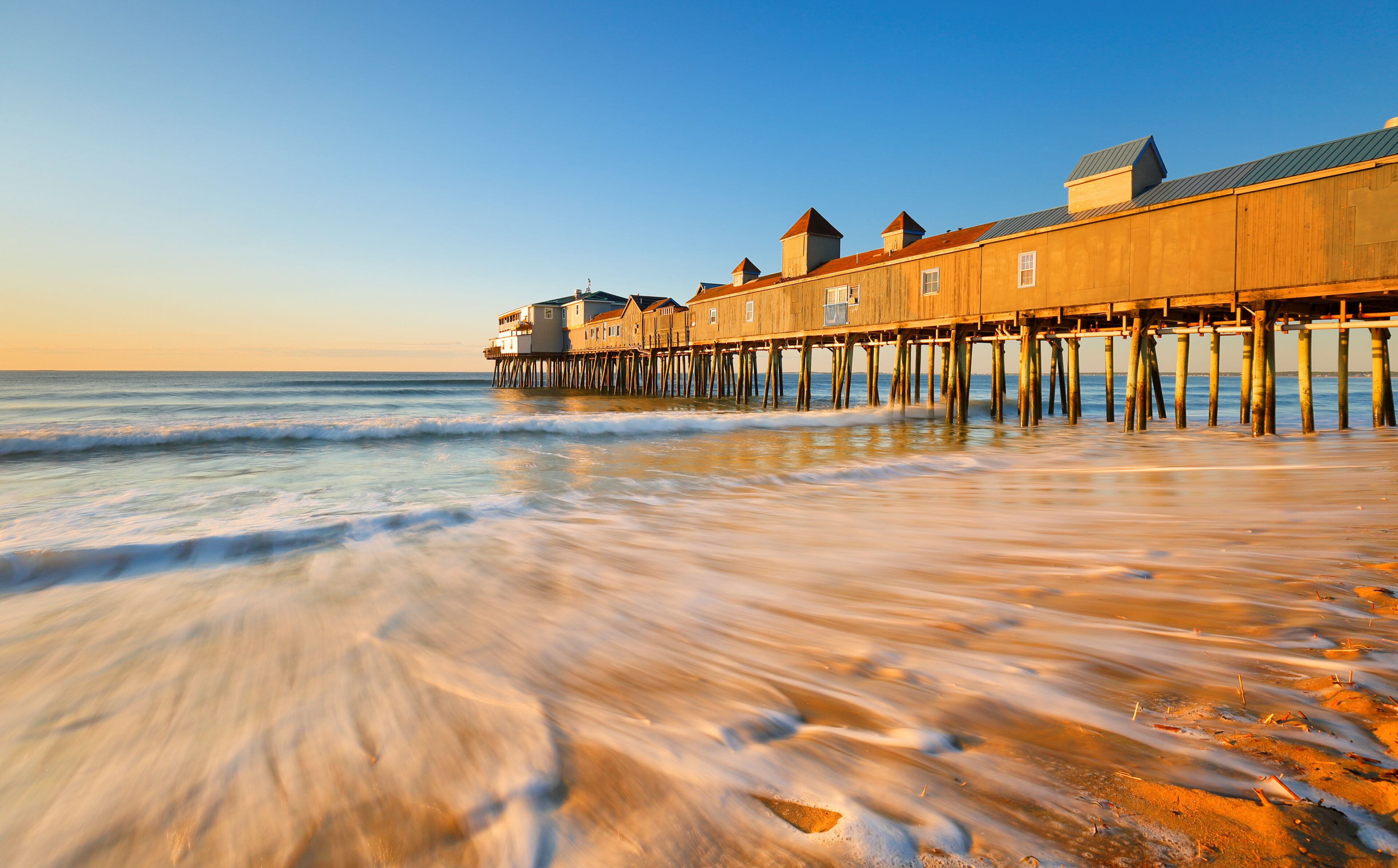 Beautiful sunrise over Old Orchard Beach Pier, Saco Maine USA. The wooden pier on the beach contains many other tourist businesses, including a variety of souvenir shops.