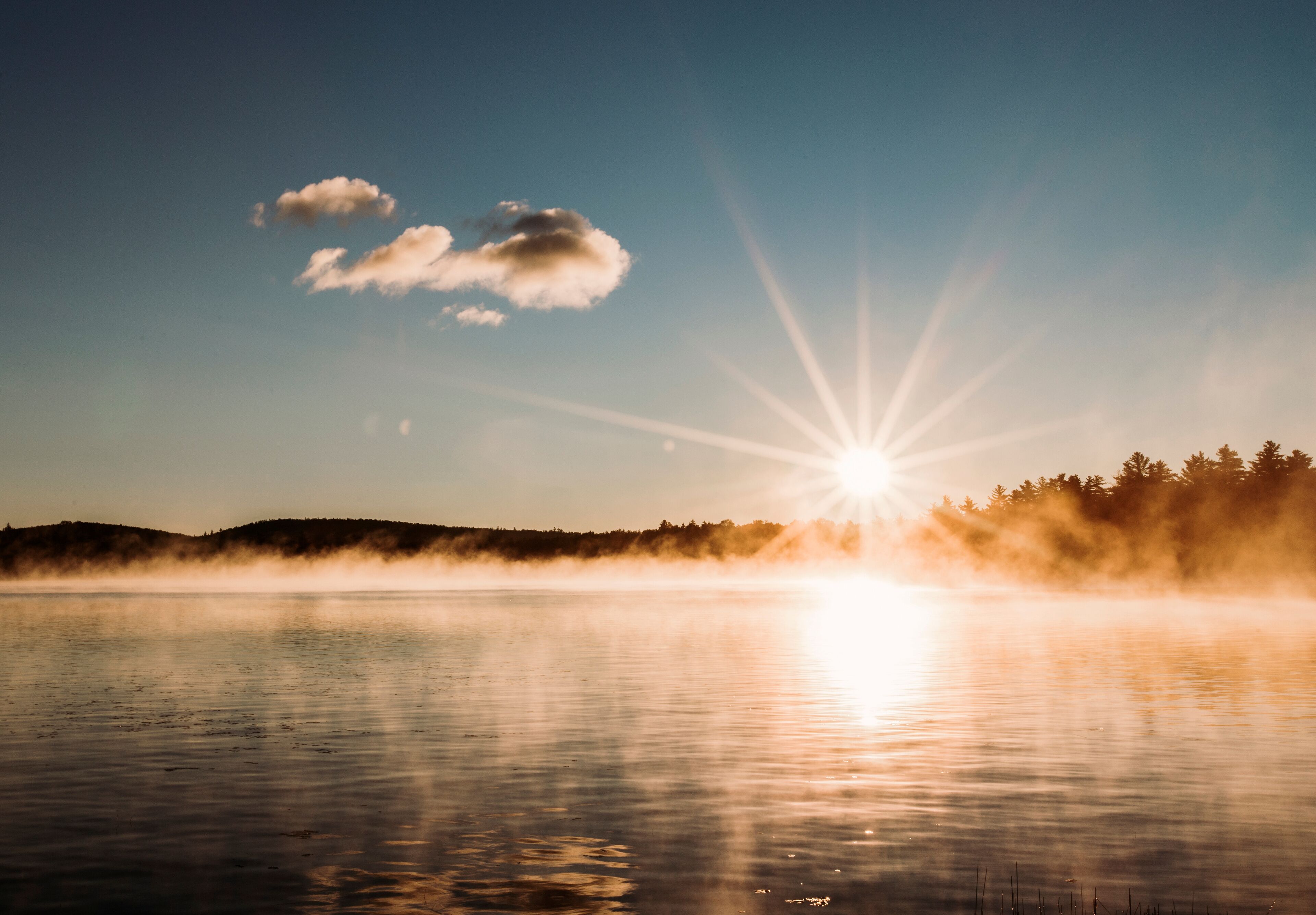 rising sun star over peaceful misty and foggy lake in Maine woods