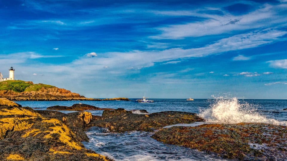 A lighthouse on a rocky outcrop with the ocean in the background.