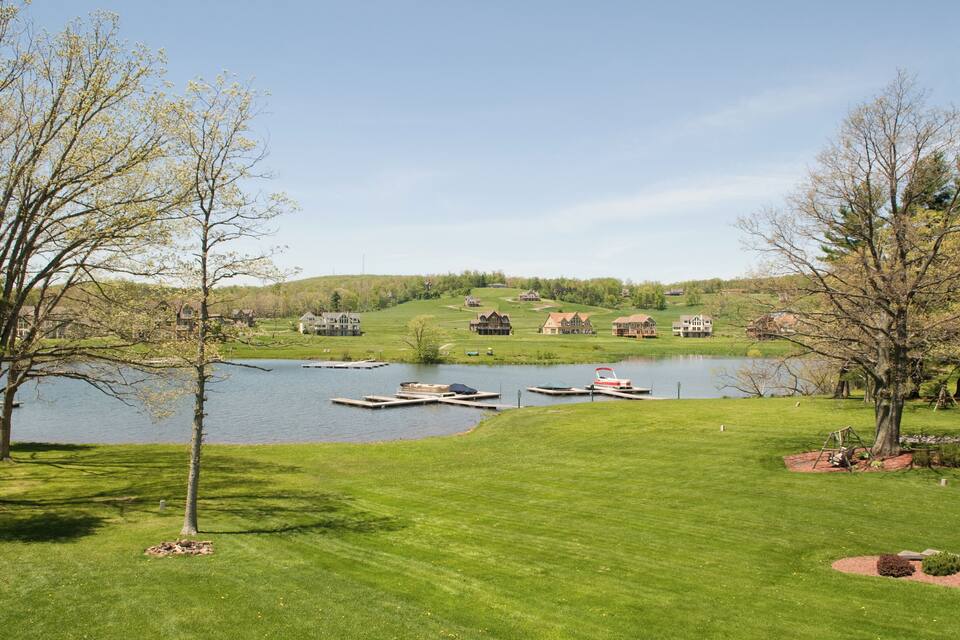 A lakeside view with boats, houses, and a grassy area.