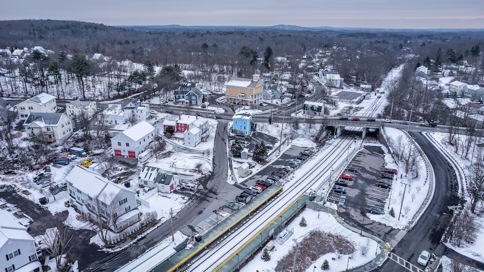 A snowy town with a train station, a highway, and residential buildings.