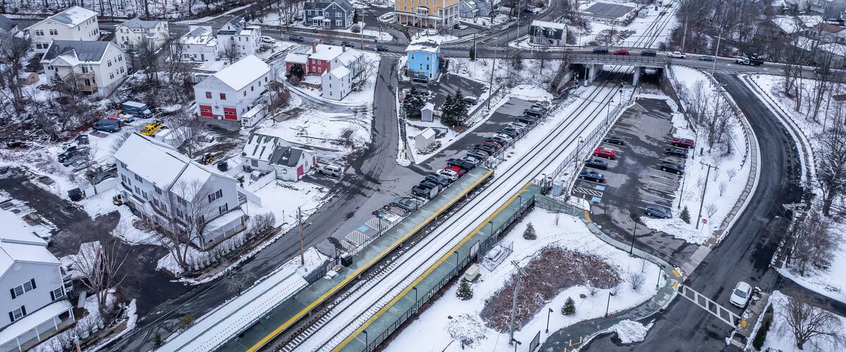 A snowy town with a train station, a highway, and residential buildings.