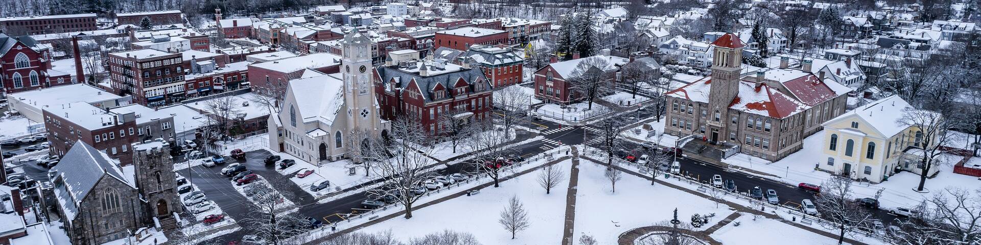 A snow-covered town with historic buildings, a prominent church, and a large clock tower.