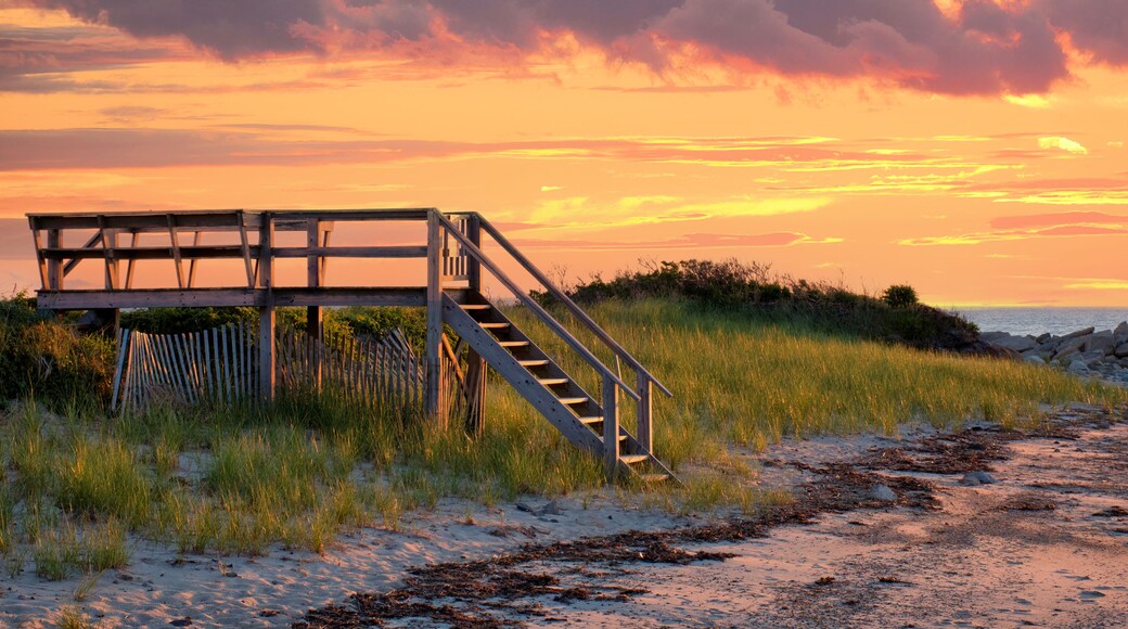 Lovely Cape Cod beach scene with colorful sunlit clouds and sun about to drop below the horizon. Vibrant summer sunset captured at Corporation Beach in Dennis, Massachusetts.