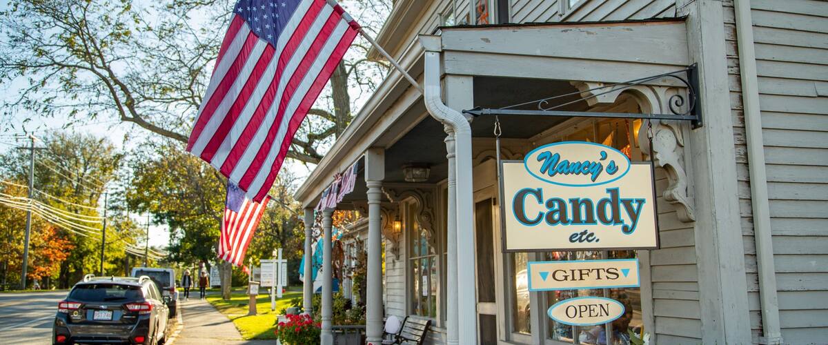A storefront with a sign reading "Nancy's Candy" and a large American flag.