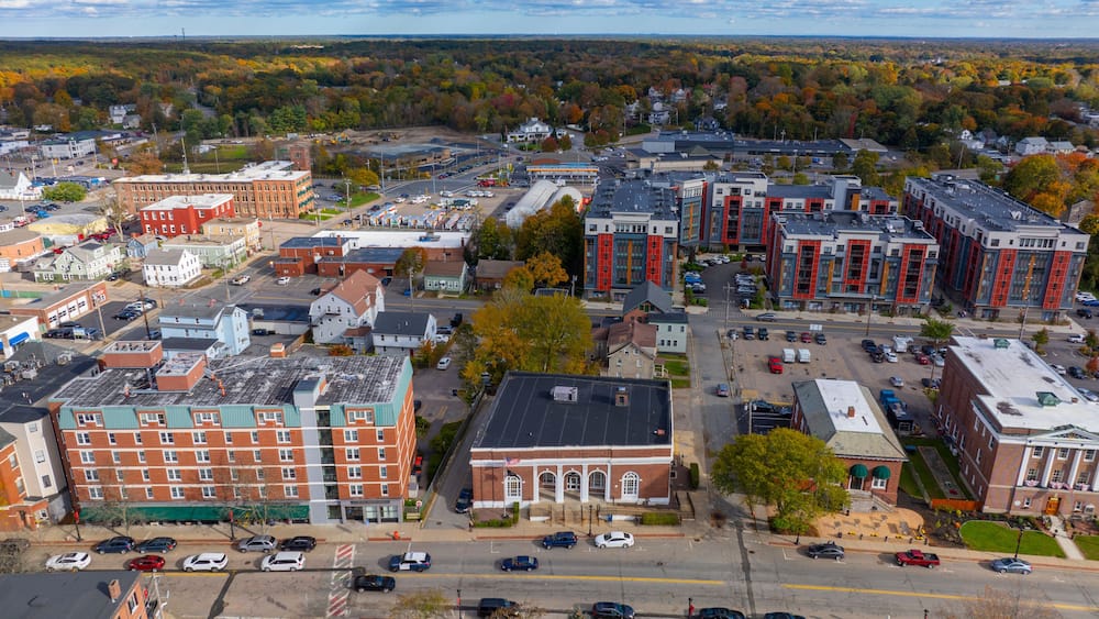 A town with historic buildings, a parking lot, and autumn foliage in the background.