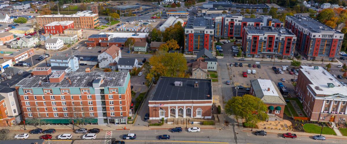 A town with historic buildings, a parking lot, and autumn foliage in the background.