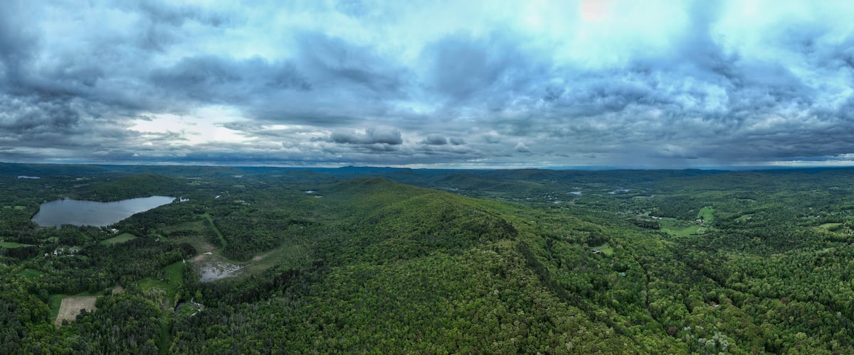 A lush green landscape with a lake and rolling hills under a cloudy sky.