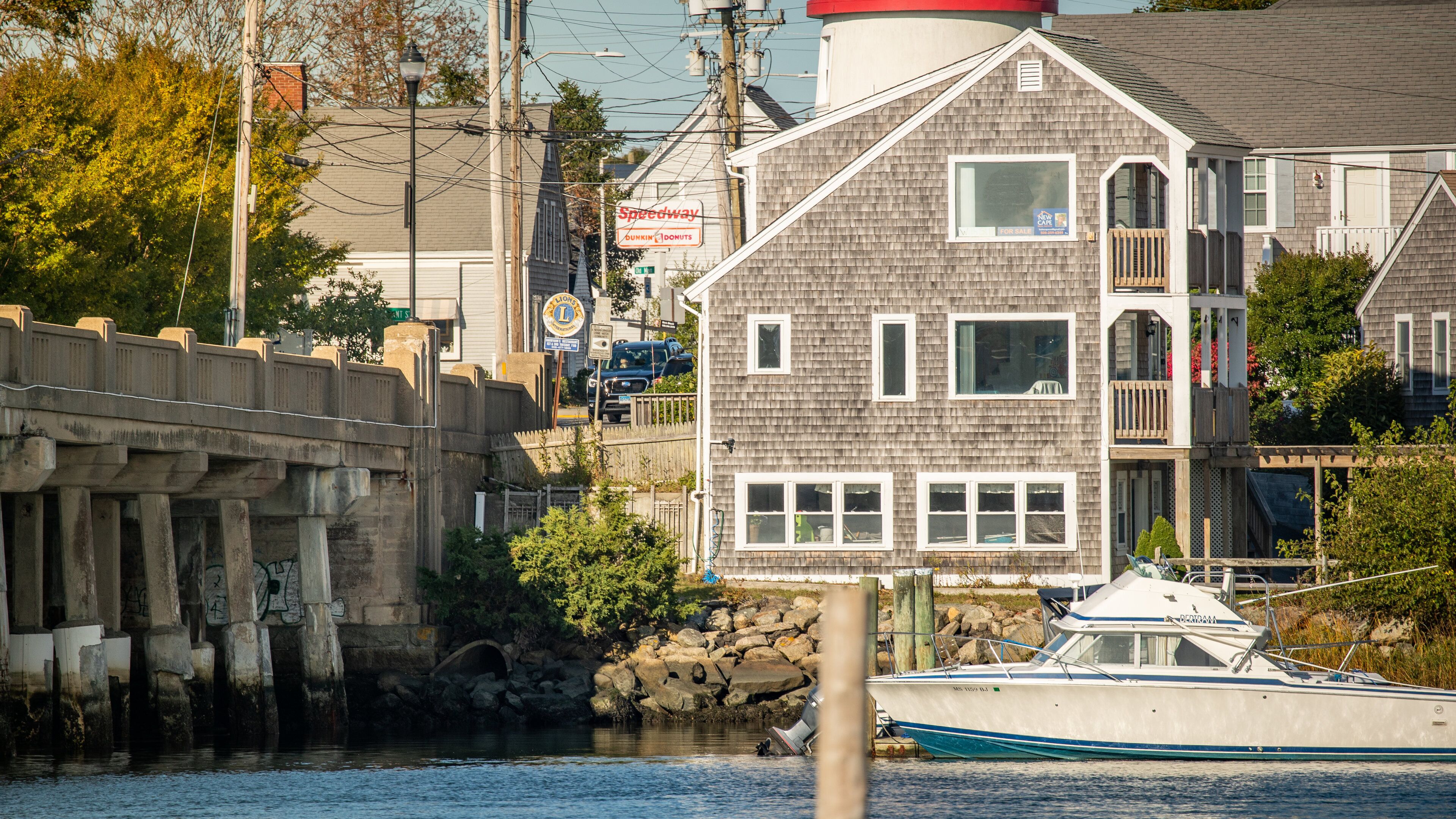 A waterfront with a boat docked, a bridge, and a building with a 'Speedway' sign.