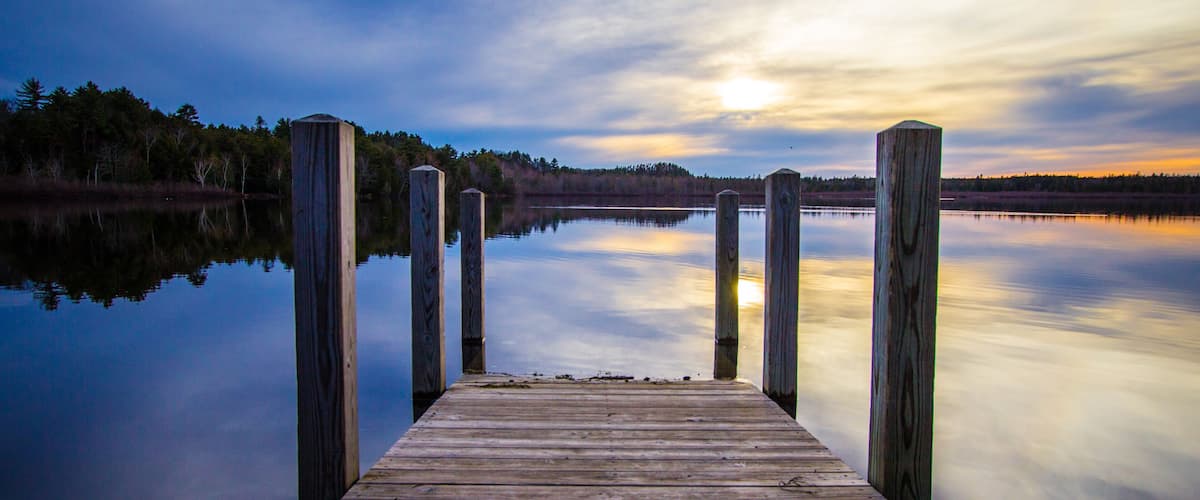 Summer Sunset Lake.. Sunset reflected in the blue water of Brevort Lake with wooden dock in the foreground. Brevort Lake is part of the Hiawatha National Forest of Michigan.
