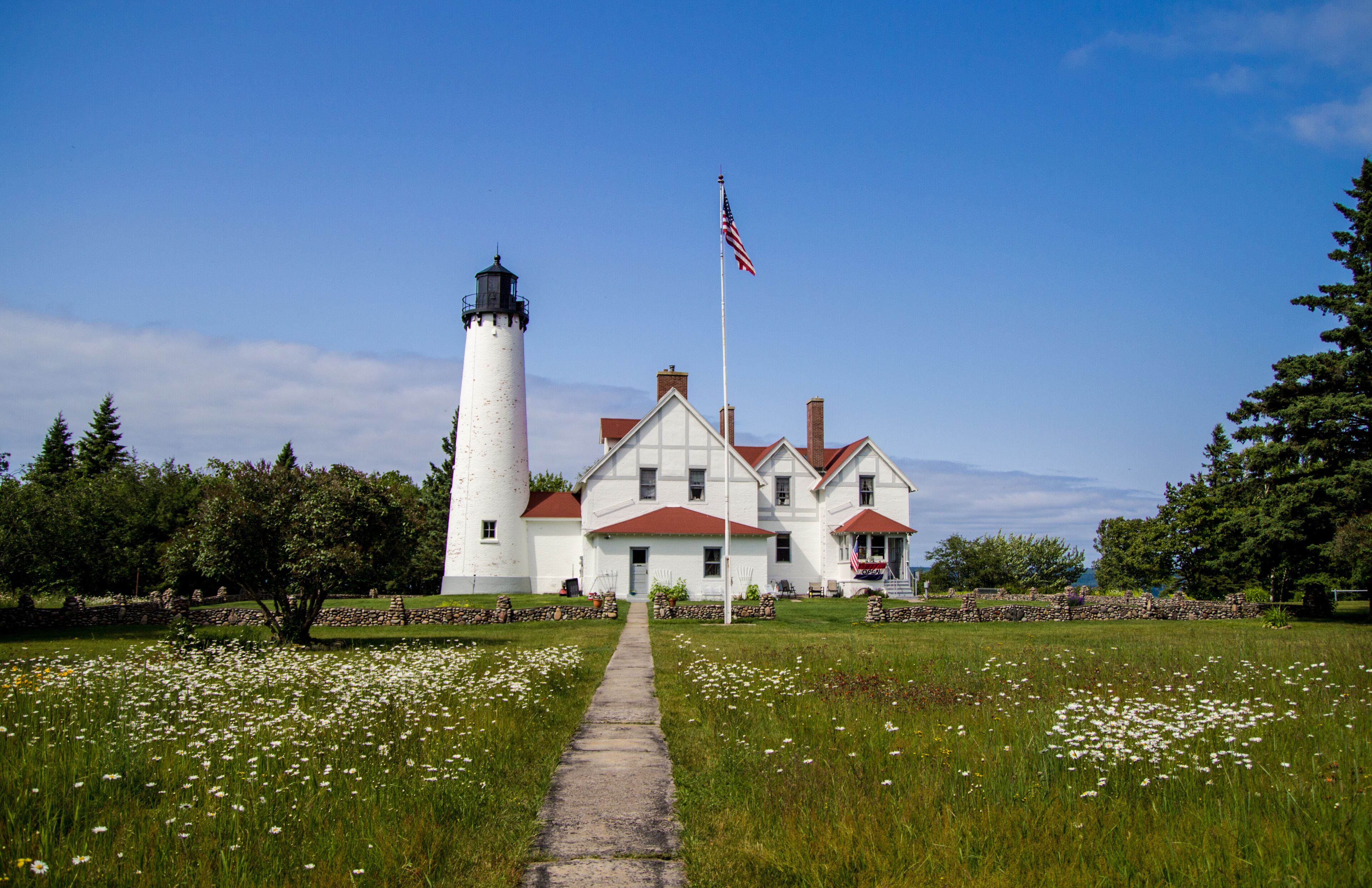 Scenic Michigan Lighthouse Landscape. Wildflowers frame a scenic lighthouse on the shore of Lake Superior. The Point Iroquois Lighthouse is a historical scenic site in the Hiawatha National Forest.