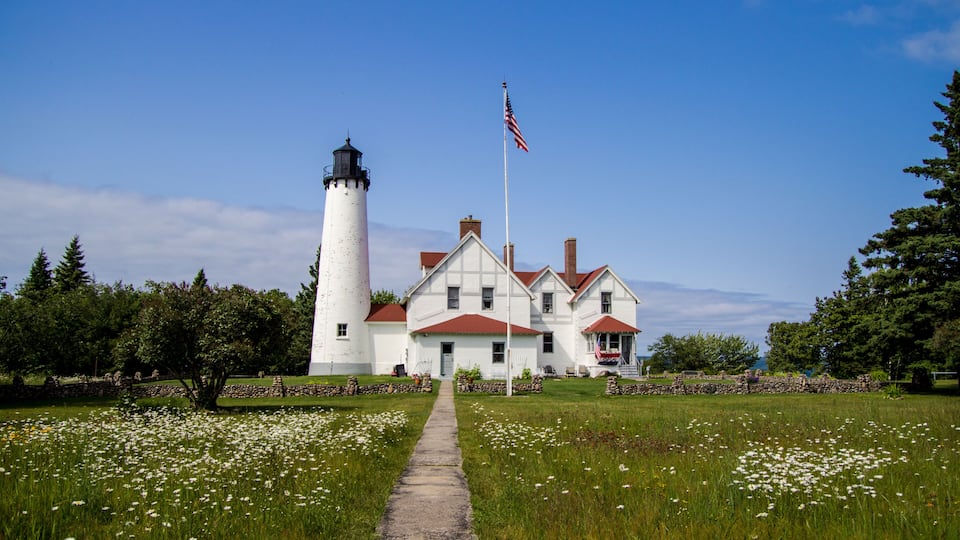 Scenic Michigan Lighthouse Landscape. Wildflowers frame a scenic lighthouse on the shore of Lake Superior. The Point Iroquois Lighthouse is a historical scenic site in the Hiawatha National Forest.