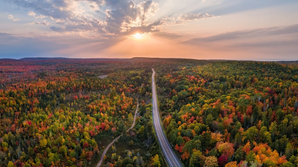 A highway winding through a forest with autumn foliage.