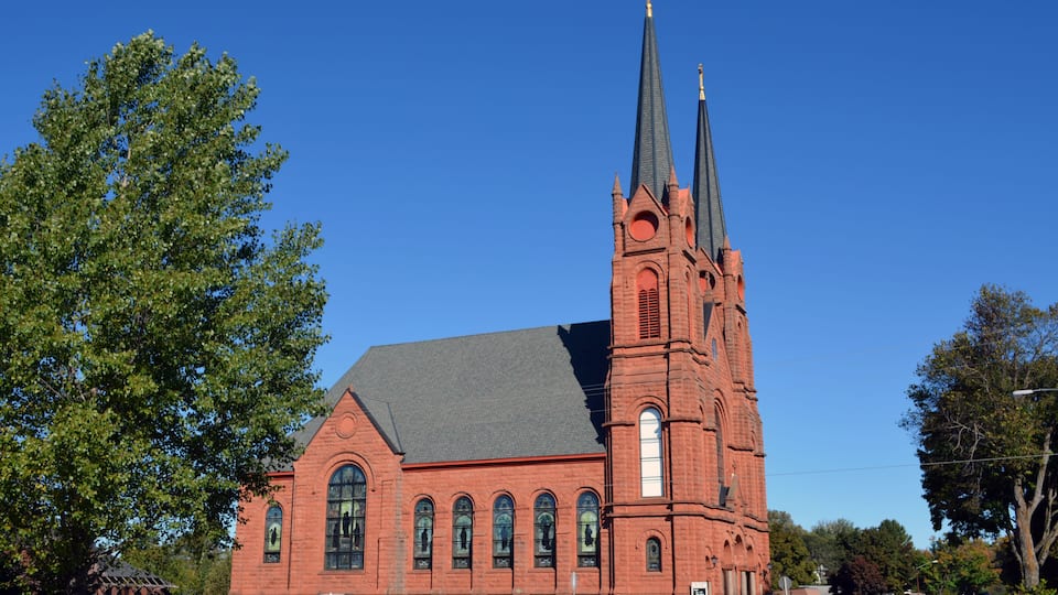 A red brick church with two spires and arched windows.