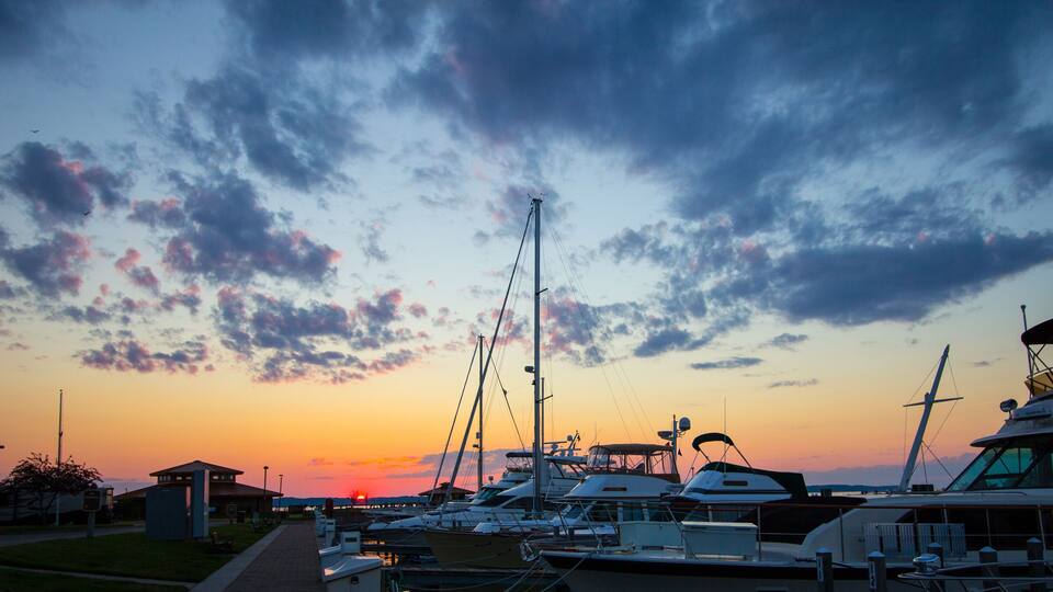 A marina at sunset with boats docked and a clear sky.