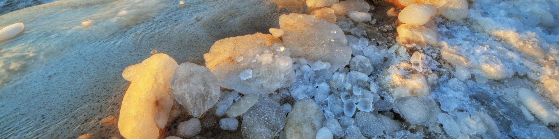 Landscape of iced winter shoreline of Lake Michigan with splashing wave, Saugatuck Dunes State Park, Michigan, USA