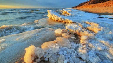 Landscape of iced winter shoreline of Lake Michigan with splashing wave, Saugatuck Dunes State Park, Michigan, USA