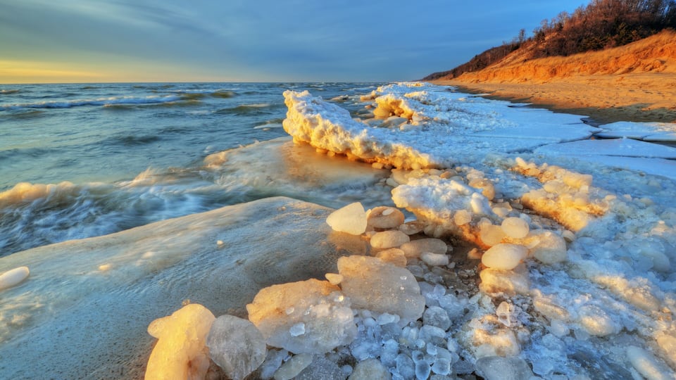 Landscape of iced winter shoreline of Lake Michigan with splashing wave, Saugatuck Dunes State Park, Michigan, USA